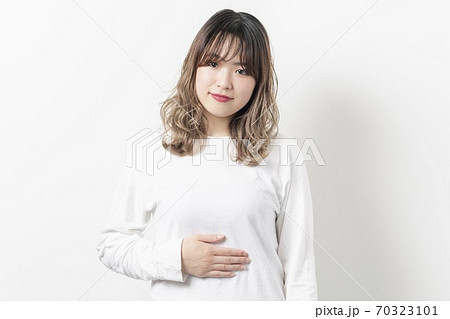 お腹に手を当てる若い女性 70323101