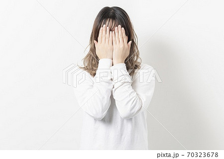 手で顔を隠す若い女性 70323678