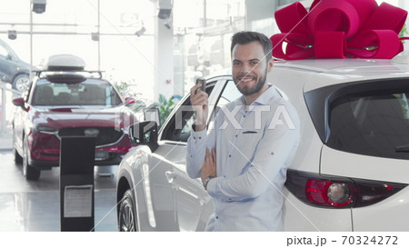 Handsome male driver holding car keys to his new auto at the dealership 70324272