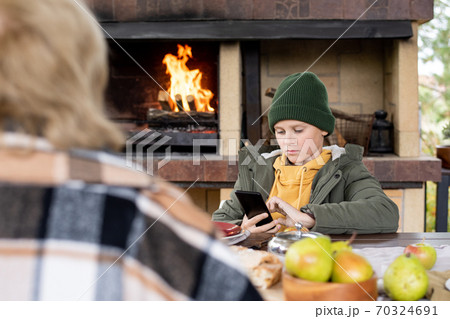 Serious clever schoolboy in beanie and warm jacket scrolling in smartphone Serious clever schoolboy in beanie and warm jacket scrolling in smartphone 70324691