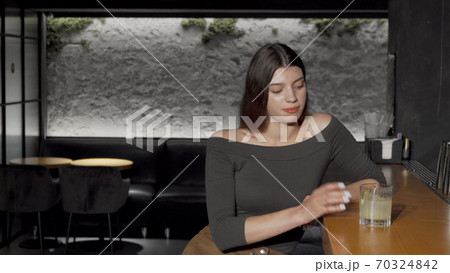 Young beautiful woman drinking cocktail at the bar counter 70324842