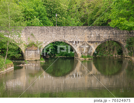 An old stone bridge reflected in the water 70324975