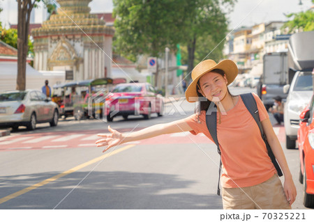 Asian woman, a tourist people hailing a taxi or a cab, travelling or waving a hand on street road in Bangkok City, Thailand in holiday vacation. Lifestyle activity concept. Asian woman, a tourist people hailing a taxi or a cab, travelling or waving a hand on street road in Bangkok City, Thailand in holiday vacation. Lifestyle activity concept. 70325221