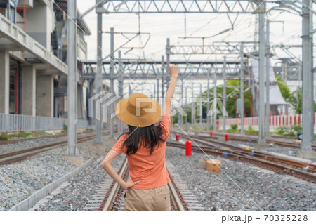 Asian woman, a tourist people, travelling in train or tram on railway with utility poles tower and cable wires in terminal station in urban city in public transportation. 70325228