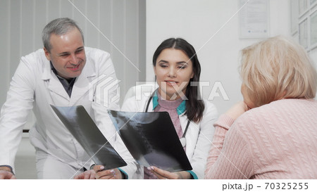 Two doctors examining x-ray scans of elderly woman 70325255
