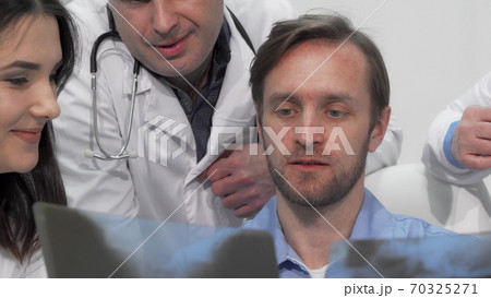 Sliding cropped shot of medical team examining x-ray or MRI scan together 70325271