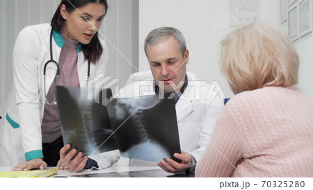 Two doctors examining x-ray scans of a senior patient 70325280