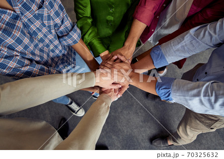 Top view of different ethnicity business people doing fists bump, celebrating success while standing in the office Top view of different ethnicity business people doing fists bump, celebrating success while standing in the office 70325632