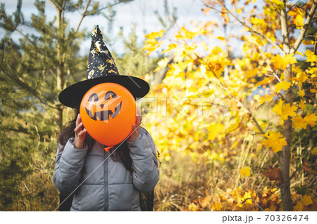 Halloween kids. Little girl with jack o' lantern in witch hat with pumpkin. Toddler kid in witch costume playing in autumn park. Halloween kids. Little girl with jack o' lantern in witch hat with pumpkin. Toddler kid in witch costume playing in autumn park. 70326474