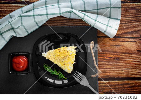 piece of omelet on black plate with ketchup. piece of omelet on black plate with ketchup. 70331082