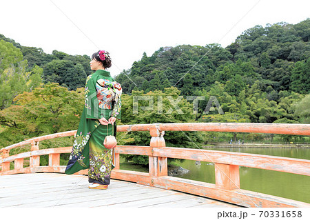 橋の上に立つ緑色の成人振袖を着た日本人女性 70331658