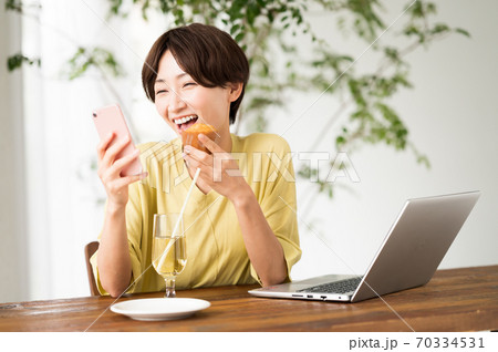 カフェでスウィーツを食べながらテレワークする女性 カフェでスウィーツを食べながらテレワークする女性 70334531