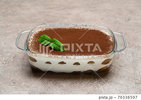 Traditional Italian Tiramisu dessert in glass baking dish on concrete background Traditional Italian Tiramisu dessert in glass baking dish on concrete background 70336507