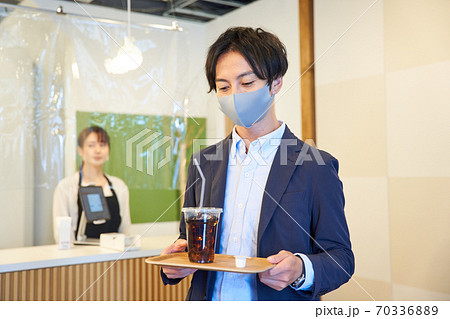 カフェでアイスコーヒーを買う青年 70336889