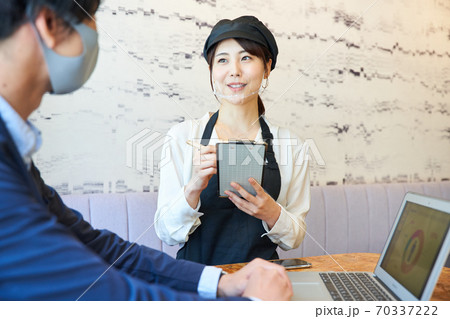 カフェで透明マスクをしてオーダーをとる女性 カフェで透明マスクをしてオーダーをとる女性 70337222