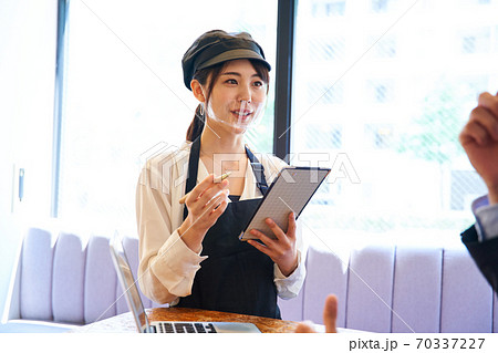 カフェで透明マスクをしてオーダーをとる女性 70337227
