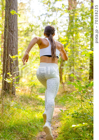 Female Running In Woodland During Outdoor Workout 70338235
