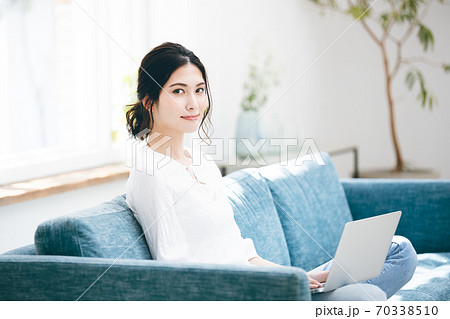 ソファーでノートパソコンを使う若い女性 70338510