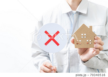 家の模型とバツサインを持つ作業着の男性 家の模型とバツサインを持つ作業着の男性 70340516