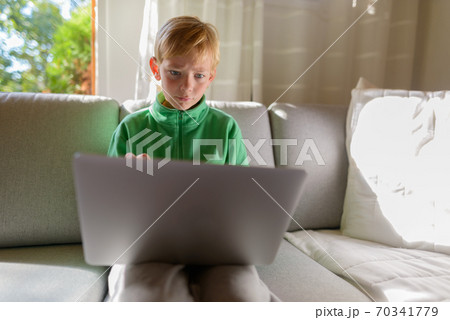 Young handsome boy using laptop on the couch at home 70341779
