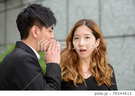 Young Asian business couple whispering together in the city 70344613