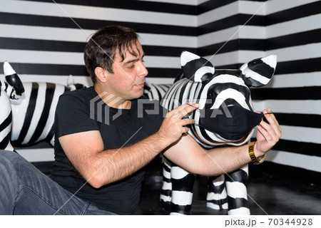 Persian man giving mask to his piggy friend for protection inside black and white room 70344928