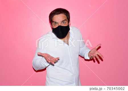 Stressed Persian businessman with mask shrugging shoulders against pink wall 70345002