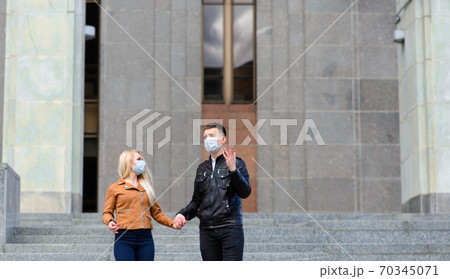 Young couple in protective medical mask on face outdoor at street. Guy and girl in virus protection. Young couple in protective medical mask on face outdoor at street. Guy and girl in virus protection. 70345071