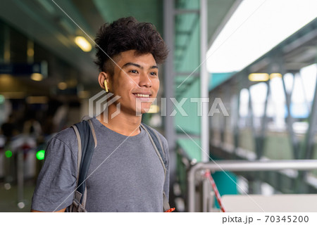 Happy young Asian tourist man as backpacker thinking at the sky train station 70345200