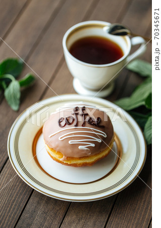 Coffee glazed donut with tea on the wooden table Coffee glazed donut with tea on the wooden table 70345671