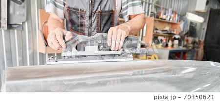 The mechanic works with a grinding tool. Sanding of car elements. Garage painting car service. Repairing car section after the accident. The mechanic works with a grinding tool. Sanding of car elements. Garage painting car service. Repairing car section after the accident. 70350621