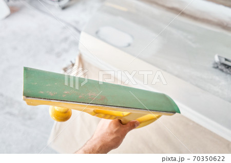 The mechanic works with a grinding tool. Sanding of car elements. Garage painting car service. Repairing car section after the accident. 70350622