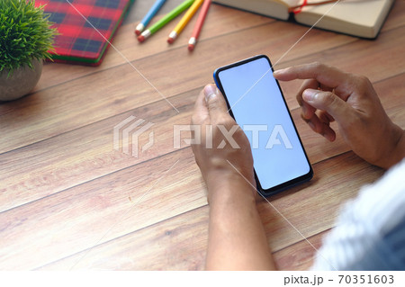 Rear view of hand holding smart phone on wooden background  70351603