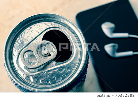 Open cold beer can with water drops near smartphone and earphones. Open cold beer can with water drops near smartphone and earphones. 70352588