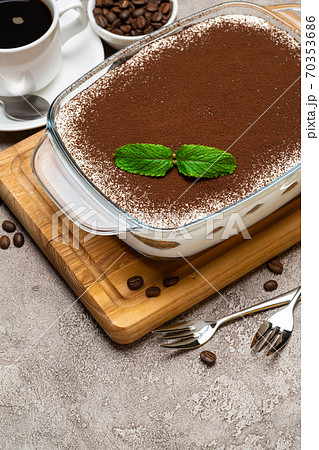 Traditional Italian Tiramisu dessert in glass baking dish, cup of fresh espresso coffee and savoiardi cookies on concrete background Traditional Italian Tiramisu dessert in glass baking dish, cup of fresh espresso coffee and savoiardi cookies on concrete background 70353686
