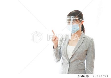 フェイスシールドをしてポイントを指差す若いビジネスウーマン 70353794