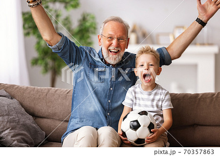 Excited grandfather and grandson watching football match on TV. 70357863