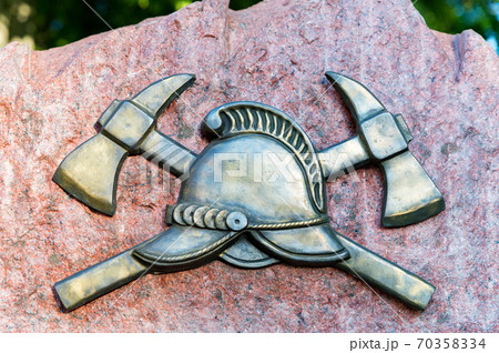 Close up of metal symbol of firefighters on a stone slab Close up of metal symbol of firefighters on a stone slab 70358334