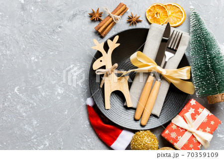 Top view of holiday dinner decorated with dried fruit and cinnamon on cement background. Set of plate, urensil and New Year decorations. Christmas time concept with epmty space for your design Top view of holiday dinner decorated with dried fruit and cinnamon on cement background. Set of plate, urensil and New Year decorations. Christmas time concept with epmty space for your design 70359109