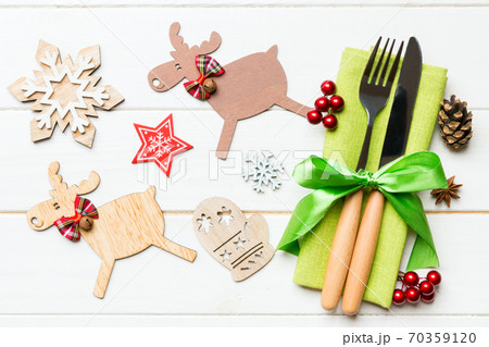 New year set of fork and knife on napkin. Top view of christmas decorations and reindeer on wooden background. Close up of holiday family dinner concept 70359120