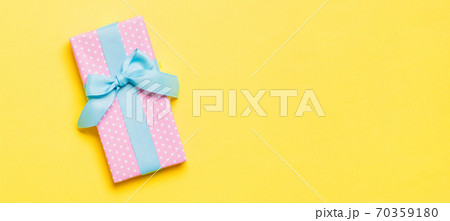 Top view Christmas present box with blue bow on yellow background with copy space 70359180