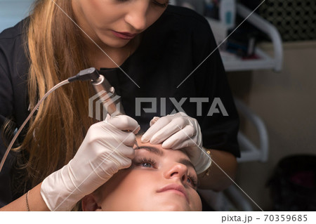 Permanent eyebrow makeup. Cosmetologist applying tattooing of eyebrows. Permanent eyebrow makeup. Cosmetologist applying tattooing of eyebrows. 70359685