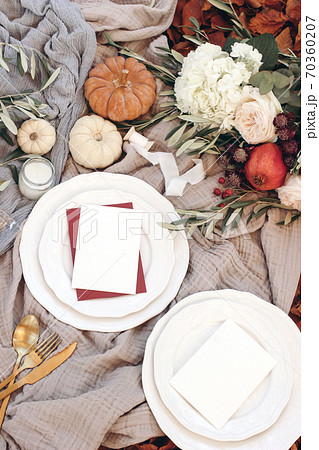 Autumn table setting with golden cutlery, olive branches and porcelain plates. Pumpkins and pomegranate fruit. Blank cards mockups. Fall, Thanksgiving and Rosh Hashanah celebration concept. 70360207