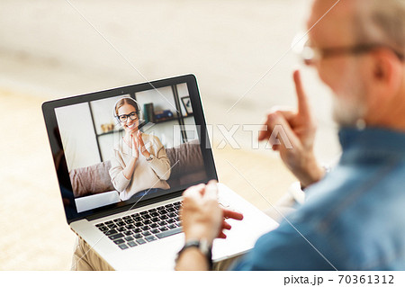 Senior man telling funny story to daughter online. 70361312