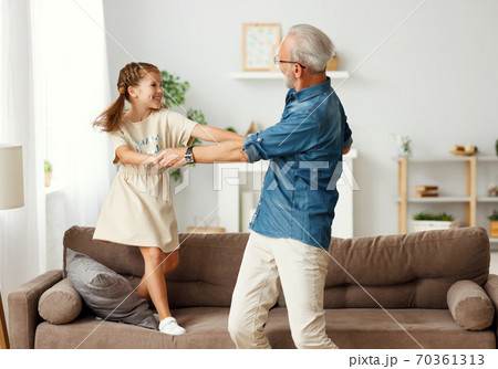 Grandfather dancing with granddaughter at home. 70361313