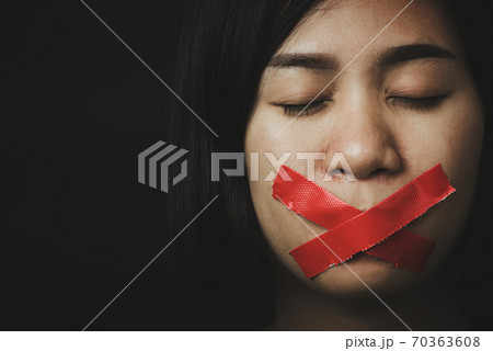 Asian woman blindfold wrapping mouth with red adhesive tape Asian woman blindfold wrapping mouth with red adhesive tape 70363608