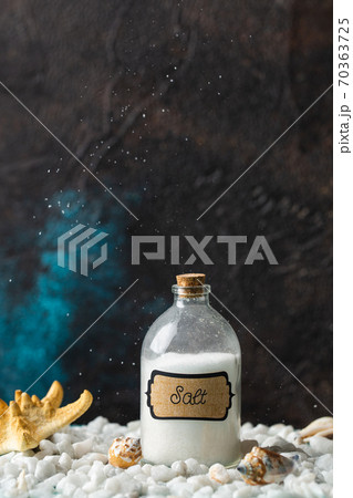 Corked, filled jar of salt and stands on white stones. Concept. Corked, filled jar of salt and stands on white stones. Concept. 70363725