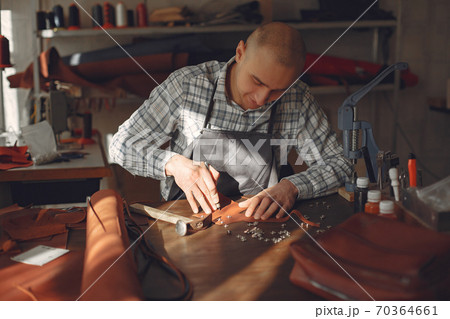 Man in a studio creates leather ware Man in a studio creates leather ware 70364661