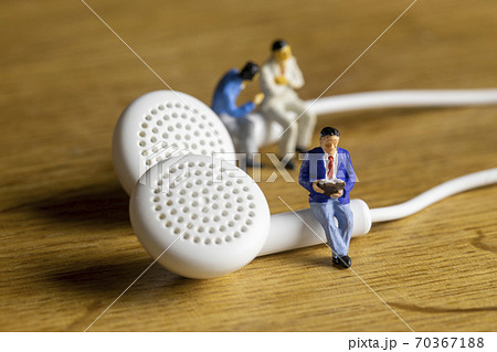 イヤホンで音声を聞くビジネスマンたち 70367188