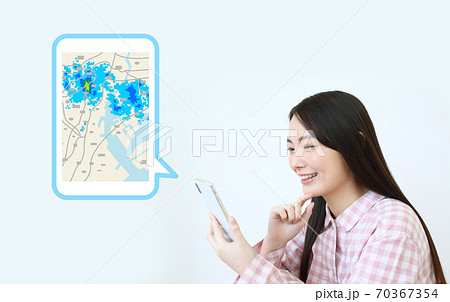 スマホで雨雲レーダーをチェックするパジャマ姿のイメージ スマホで雨雲レーダーをチェックするパジャマ姿のイメージ 70367354